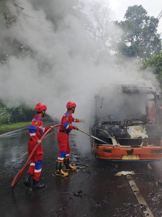 Petugas Damkar Banyumas tengah berupaya memadamkan api pada bus Mikro yang mengalami kebakaran 