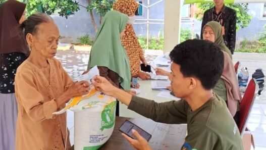Proses distribusi beras 20 kg di balai desa dengan pengawasan petugas