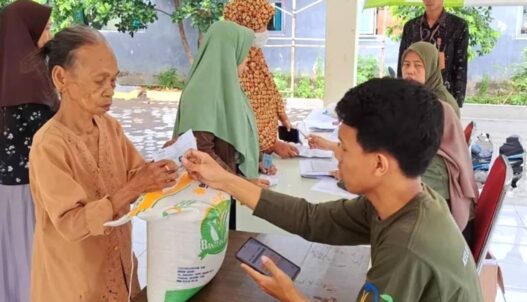 Proses distribusi beras 20 kg di balai desa dengan pengawasan petugas