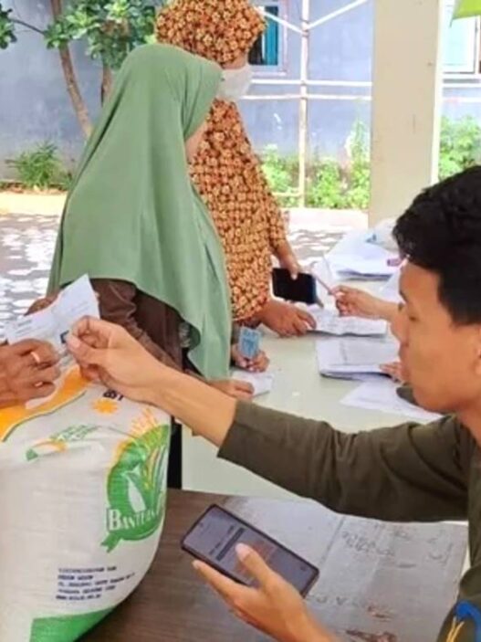 Proses distribusi beras 20 kg di balai desa dengan pengawasan petugas